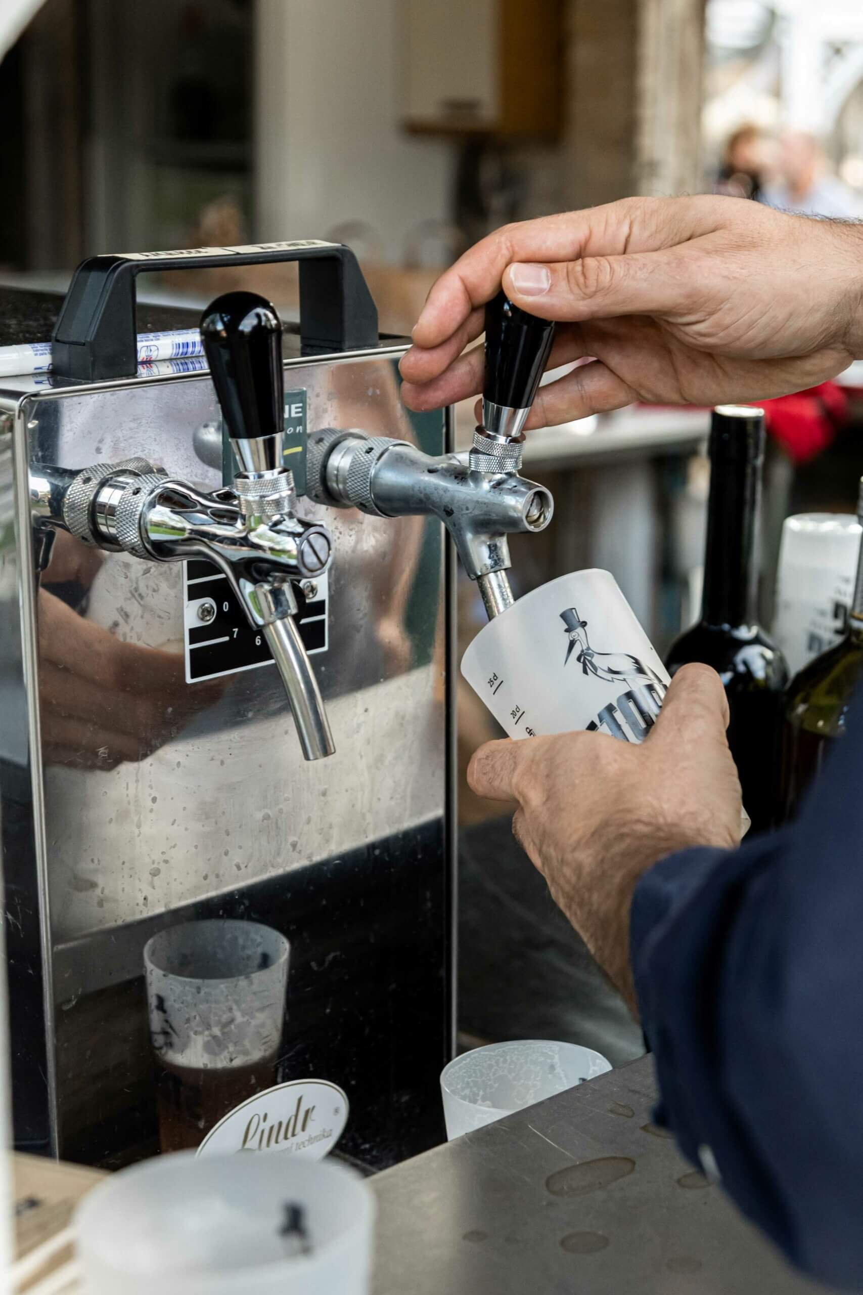 Cette photo saisit l'instant d'une main versant une bière fraîche dans une élégante chope illustrée. La tireuse à bière, en inox brillant, reflète la convivialité et la générosité d'un mariage festif dans les Vosges. La scène met en avant l'importance des moments de partage, entre amis et famille, autour d'une bonne bière artisanale locale. Un clin d'œil parfait pour les couples amoureux des plaisirs simples et authentiques.